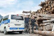 Mitarbeiter mit Elektroauto vor Brennholzstapel Bio-Fernwärme, Kuster Gebäudetechnik GmbH, Schruns
